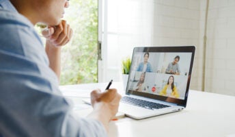 Person working on laptop with meeting on screen