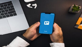 Person holding phone with Trello open on the screen