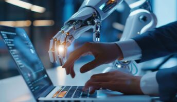 Person working on laptop, assisted by robot