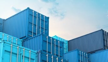 Blue containers stacked under blue sky