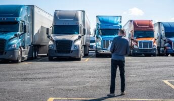 Man with back to camera looking at trucks on road