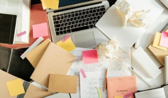 Papers piled around a laptop