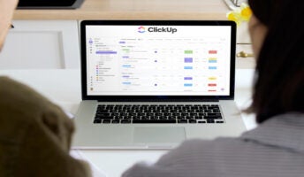 People working on laptop with ClickUp on screen