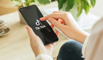 Person holding phone with TikTok logo
