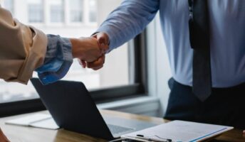 Workers in an office share a handshake.